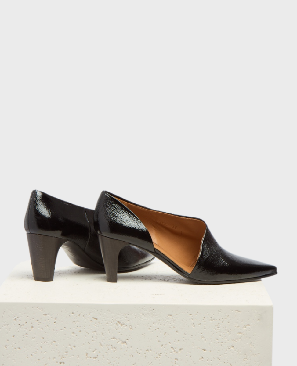 A pair of sleek, black patent leather heels with a pointed toe, mid-height block heel, and smooth, glossy finish, featuring a subtle V-cut opening and a tan interior lining.