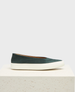 A sleek, dark green suede slip-on shoe with a smooth texture, featuring a minimalist design and a contrasting thick white rubber sole. 1