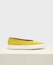 A mustard yellow suede slip-on shoe with a smooth texture, featuring a rounded toe and a thick white rubber sole. 1