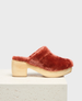 A plush, rust-colored mule with a soft, fuzzy texture and a chunky, light wooden platform heel. 2