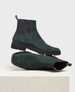 A pair of dark green suede Chelsea boots with a smooth texture, featuring elastic side panels, a pull tab at the back, a rounded toe, and a sturdy black rubber sole. 1