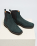 A pair of sleek, dark green suede ankle boots with a smooth texture, featuring black elastic side panels, a low heel, and a pull tab at the back for easy wear. 3