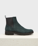 A dark green suede Chelsea boot with a smooth texture, featuring a black elastic side panel, a pull tab at the back, and a sturdy black rubber sole. 2