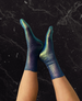 Feet wearing metallic foil silk socks against a black marble wall 7