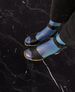 Model wearing metallic foil silk socks and black sandals standing on black marble floor 6
