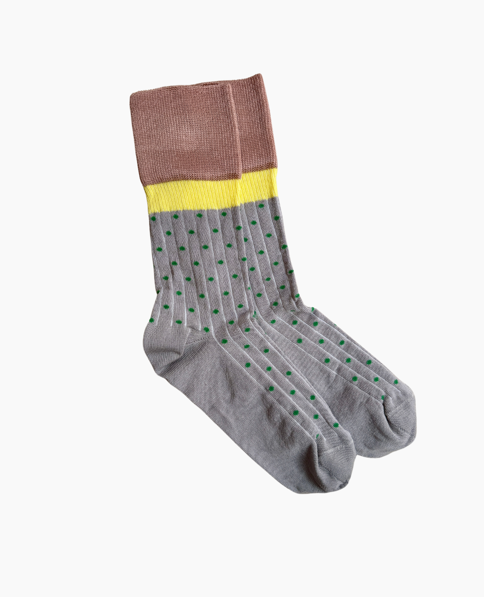 A pair of gray socks with green polka dots, featuring a yellow band and a brown cuff, made from a soft, stretchy fabric.