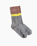 A pair of gray socks with green polka dots, featuring a yellow band and a brown cuff, made from a soft, stretchy fabric. 2