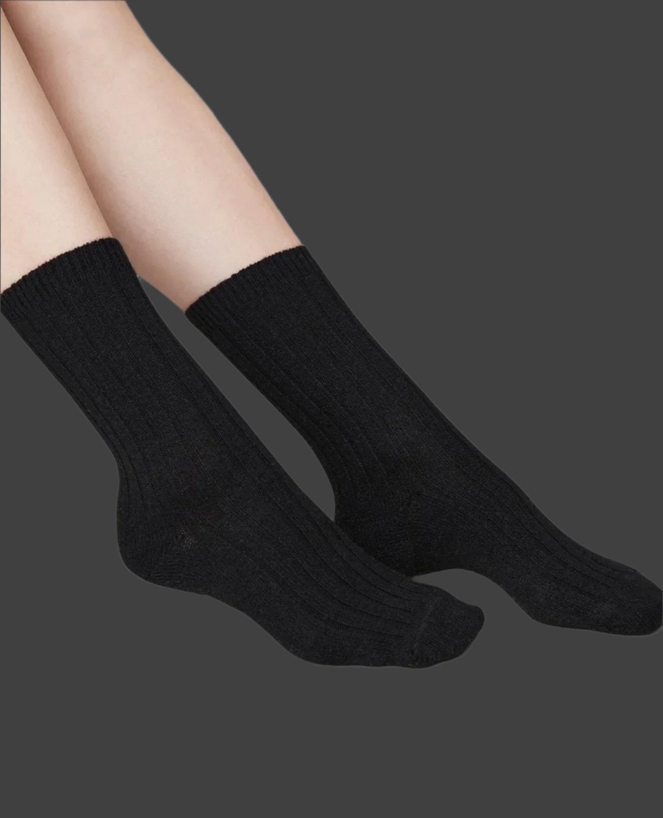 Side angle of the Swedish Stockings Bodil chunky wool socks in black shown on a model's feet 