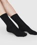 Side angle of the Swedish Stockings Bodil chunky wool socks in black shown on a model's feet  3