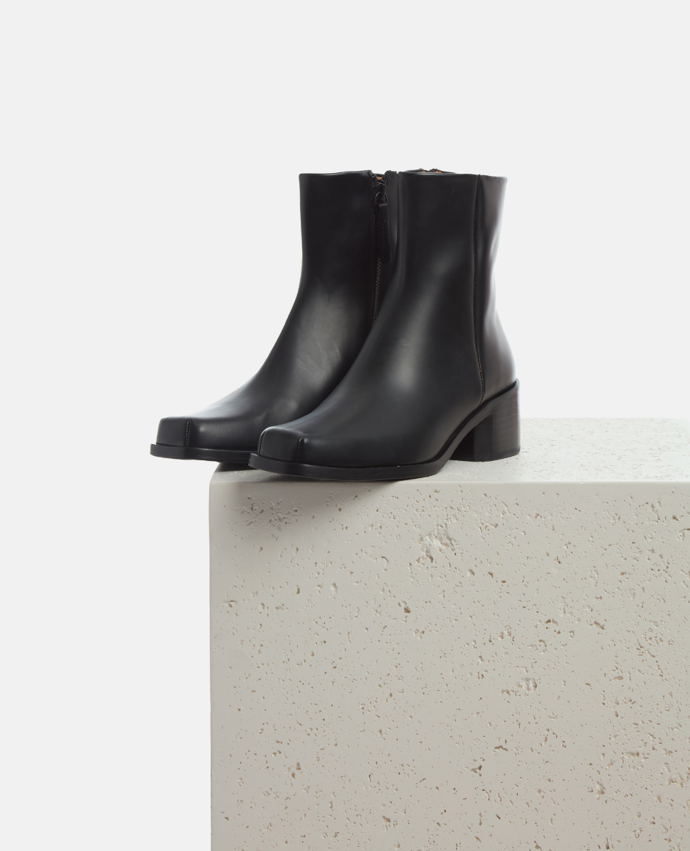 Black ankle boots on a light gray surface with a white background