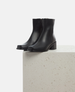 Black ankle boots on a light gray surface with a white background 4