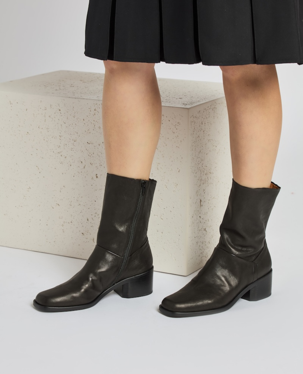 Black, mid-calf leather boots with a side zipper, square toe, and a low block heel, featuring a smooth, slightly shiny texture.