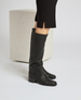 Black knee-high leather boots with a smooth texture, a rounded toe, a low block heel, and a sleek, minimalist design. 4