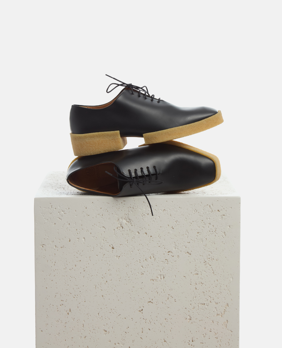 Black leather shoes with tan soles on a light gray background