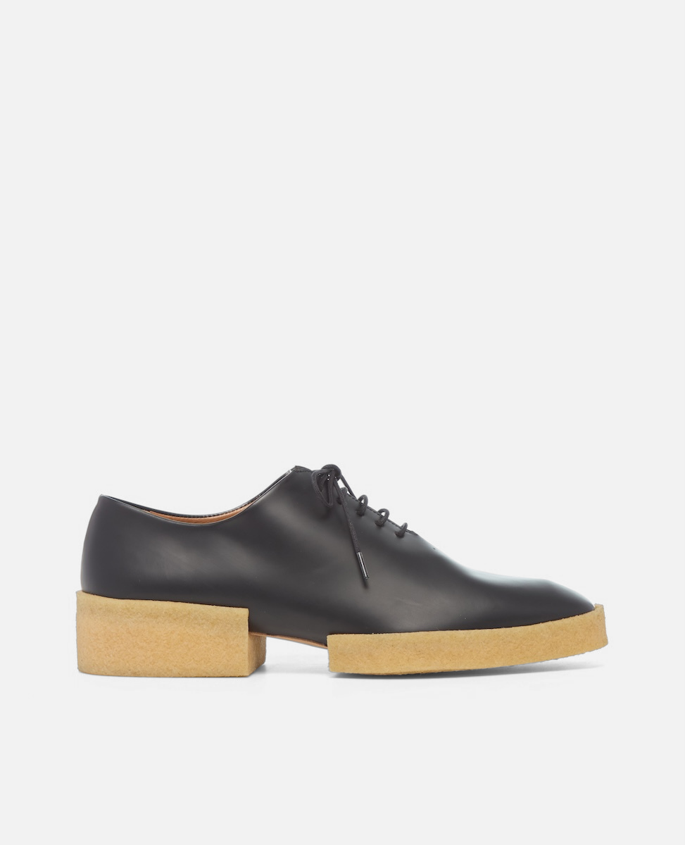 Black leather shoe with a wooden sole on a white background