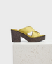 A stylish sandal featuring a mustard yellow satin crisscross strap design, a chunky cork platform heel, and a smooth, open-toe silhouette. 1