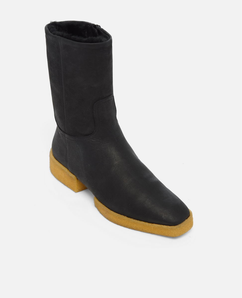 Black ankle boot with a yellow sole on a white background