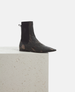 Black distressed leather boot on a white pedestal with a light gray background 3