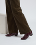 Dark brown, wide-legged pants paired with glossy, burgundy ankle boots featuring a low block heel and a sleek, pointed toe design. 5