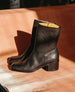 A pair of mid-calf black leather boots with a smooth texture, a square toe, a sturdy stacked  heel, and a tan interior lining. 9