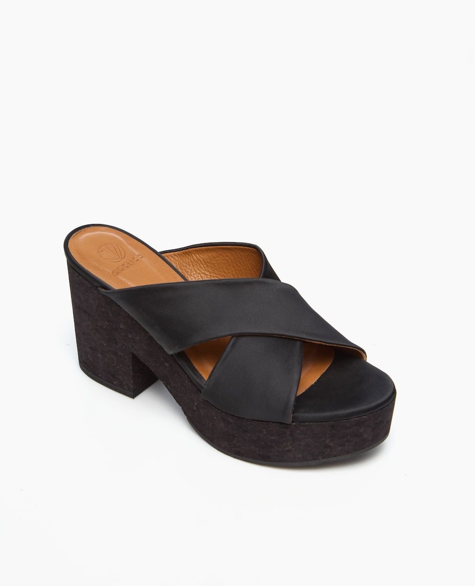 A black platform sandal with a chunky heel features wide, crisscrossing leather straps and a tan insole.