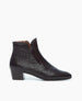 Side view of Coclico Calm Boot in amethyst patent: classic black leather grounded by a solid wood angled heel, featuring a bid front insert and an almond toe shape.  1