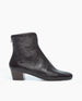 A sleek, black ankle boot with a smooth, glossy leather finish, featuring a back zipper and a low, solid wood heel. 5