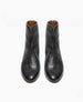 A pair of sleek, black leather ankle boots with a smooth, slightly glossy texture, almond-shaped toes, and a subtle seam running down the center of each boot. 7