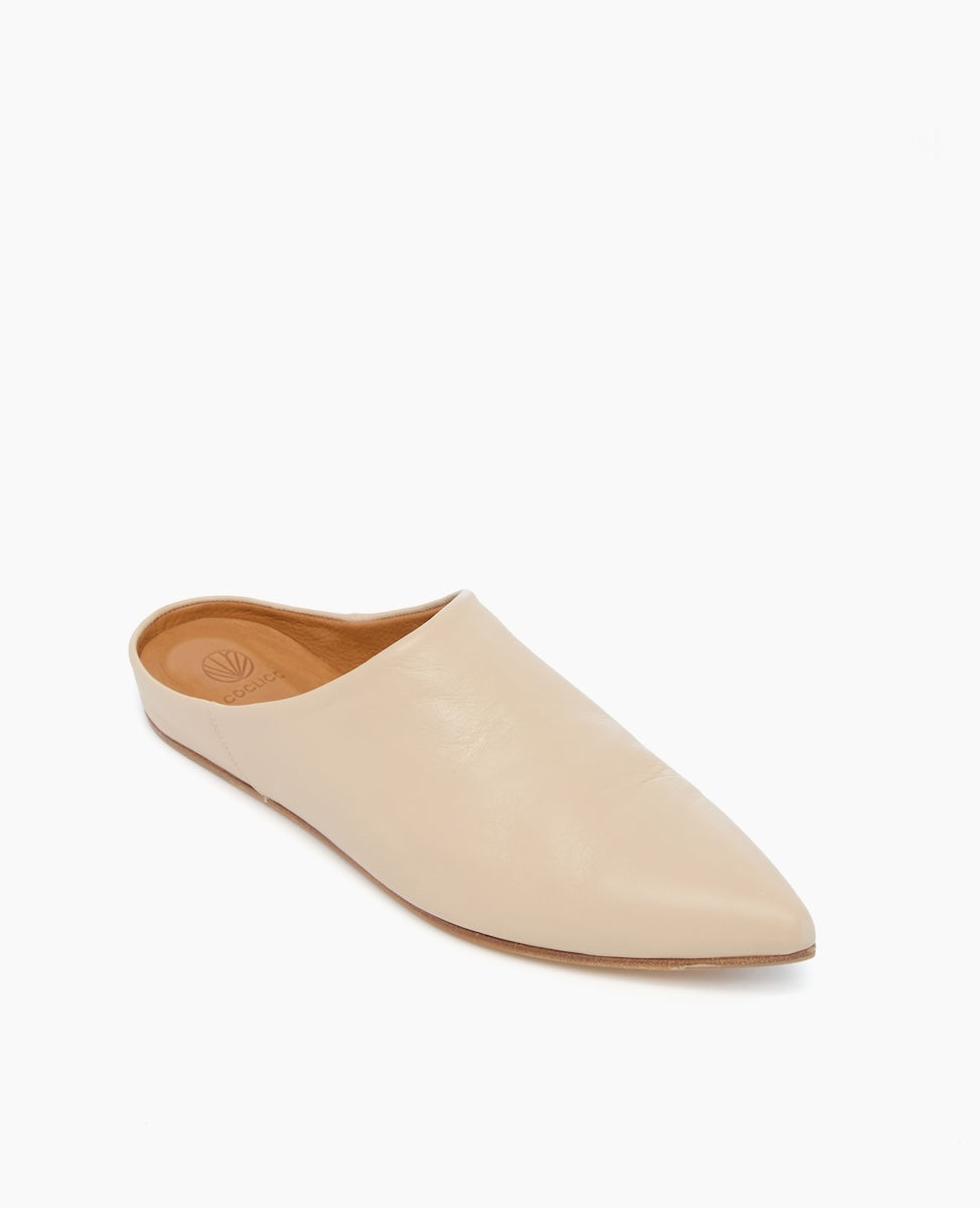 A beige, pointed-toe leather mule with a smooth texture, flat sole, and open back design.