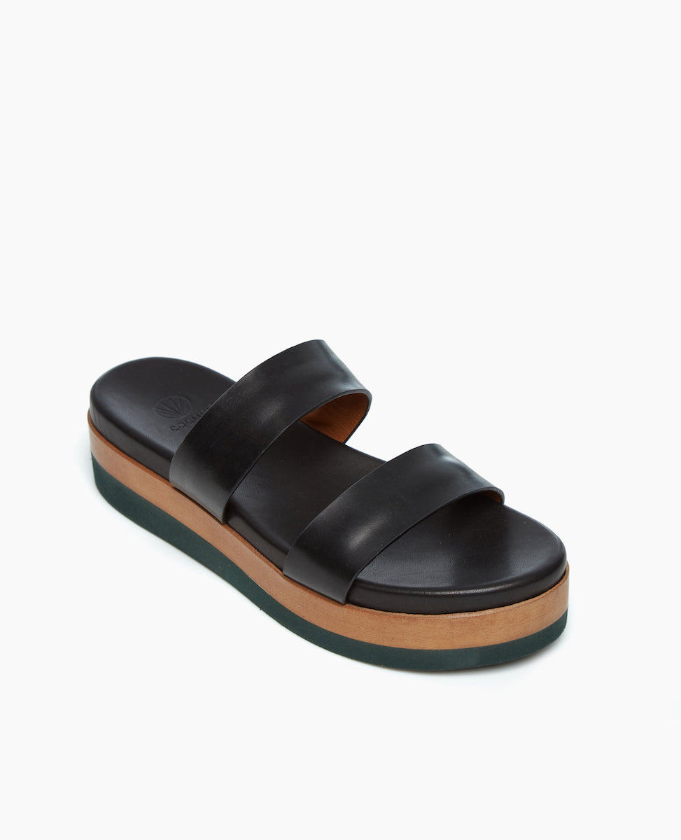 Angled view of the Dawn Wedge in Black Vacetta Leather; an easy two-strap slide upper sits atop a molded footbed and an ultra-lightweight EVA platform unit. 