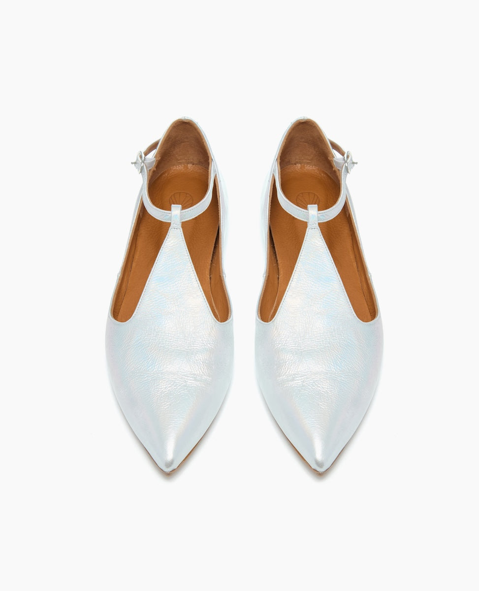 A pair of sleek, pointed-toe shoes in a glossy white finish with a unique V-shaped cutout design and an ankle strap, featuring a smooth texture and a low heel.