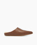 A brown leather slipper with a smooth texture, featuring a closed toe, open back, and a flat sole, lined with soft, cream-colored material for comfort. 5