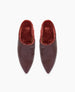 A pair of pointed-toe, dark brown leather slippers with a plush, deep red interior lining. 5