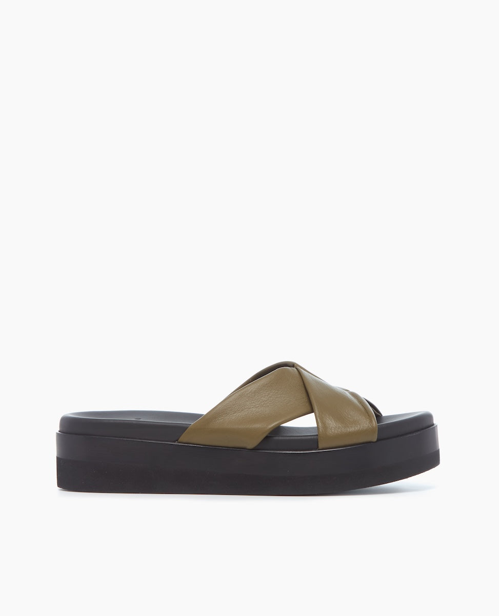 A sandal featuring a thick black platform sole and an olive green leather crisscross strap with a smooth texture.