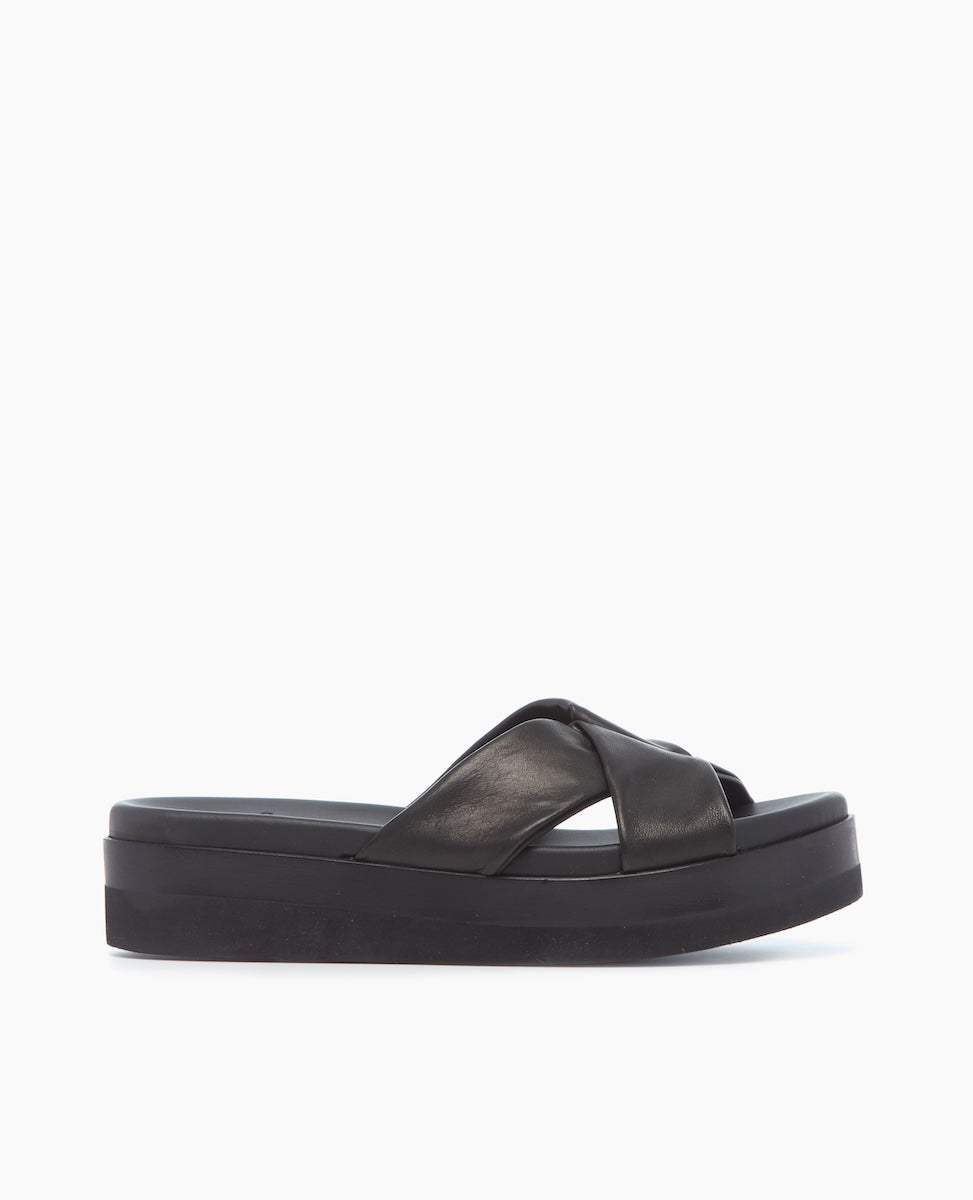 A black platform sandal featuring a thick sole, a smooth leather upper with wide crisscross straps, and an open toe design.