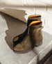 A pair of olive green suede ankle boots with a front zipper, round toe, and an airy EVA sole, featuring a contrasting tan interior lining. 8