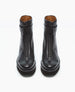 Sleek black leather ankle boots with a front zipper, round toe, an EVA sole, and a black leather strap around the ankle. 4