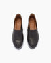 A pair of sleek, black leather slip-on shoes with a smooth texture, rounded toe, and tan interior lining, featuring a subtle logo on the insole. 3