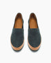 A pair of slip-on shoes with a dark green suede upper, tan leather trim around the base, and a smooth, rounded toe, featuring a minimalist design and a logo embossed on the insole. 4