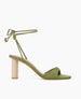 Side view of the Gilda Heel in Mosstone with dainty leather straps that cascade up the ankle finishing in a tie closure. 1