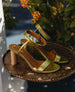 Side view of a pair of the Gina Heel in Chartreause Antiqued Patent  on a gilded plate.  9