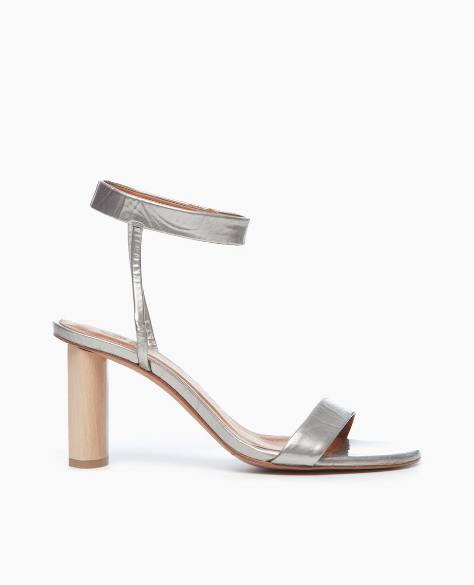 Side view of the Gina Heel in Chateau Grey Antiqued Patent, featuring a straight, narrow front strap and ankle strap that is secured with velcro for a supportive and seamless look.