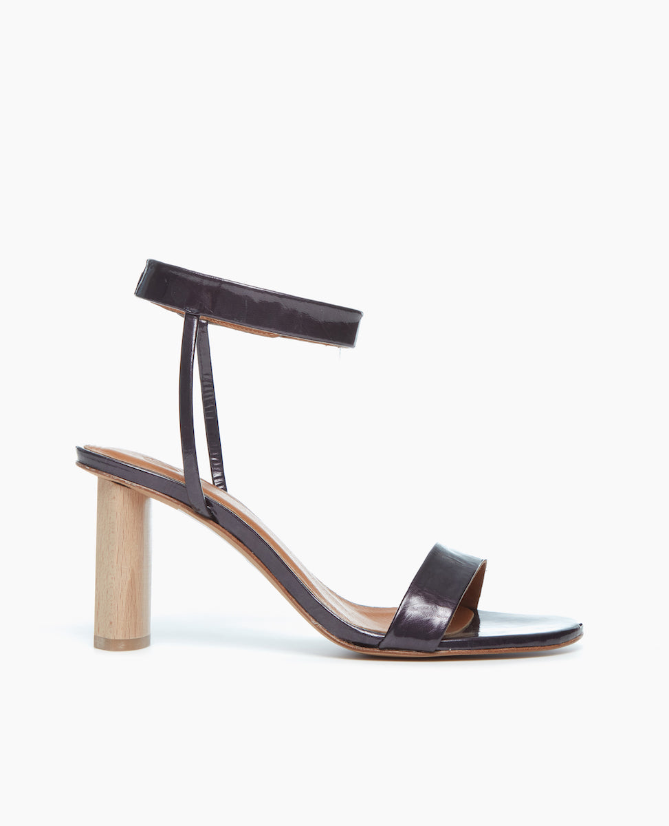 Side view of the Gina Heel in Black Pearl Patent, featuring a straight, narrow front strap and ankle strap that is secured with velcro for a supportive and seamless look.