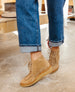 Tan suede ankle boots with a lace-up front, crepe rubber sole, and a slightly sculpted toe, worn with cuffed blue jeans. 10