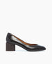 A sleek, black patent leather pump with a rounded toe, a low block heel, and a smooth, glossy finish. 7