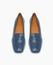 A pair of sleek, blue leather loafers with a smooth texture, almond-shaped toes, and tan insoles featuring a subtle logo imprint. 4