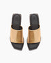 A pair of open-toed, square-heeled sandals featuring a wide, metallic gold strap across the top, with a sleek black footbed and a subtle logo embossed on the insole. 4