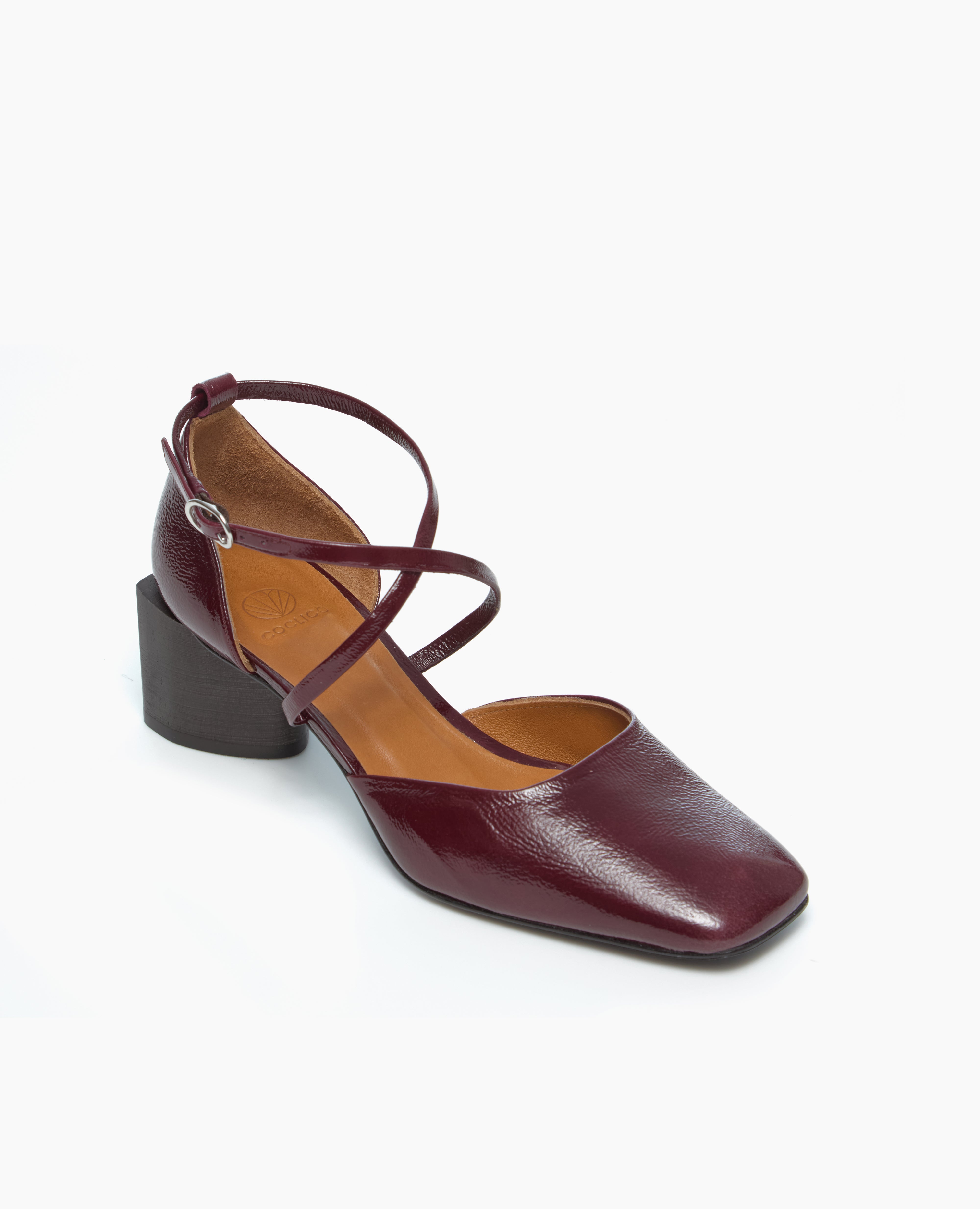 A maroon leather shoe with a square toe, crisscross ankle straps, and a chunky black heel.