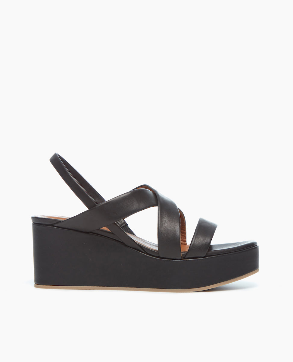 Side view of the Lylo Wedge in Black Leather featuring a lightweight, recycled cork wedge wrapped in leather. 