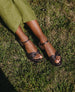Feet pictured against grass wearing the Lynn Wedge in Anthracite Shimmer Suede.  4